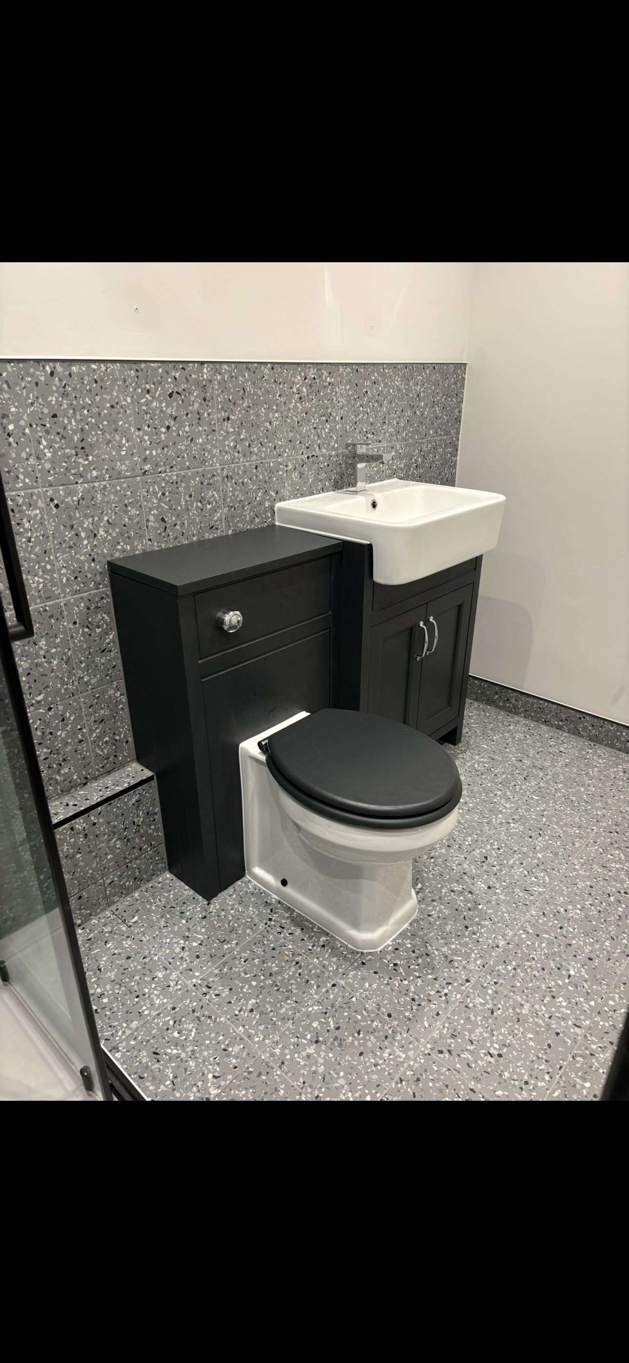 Terrazzo tiled bathroom with dark shaker vanity unit, basin and black toilet seat