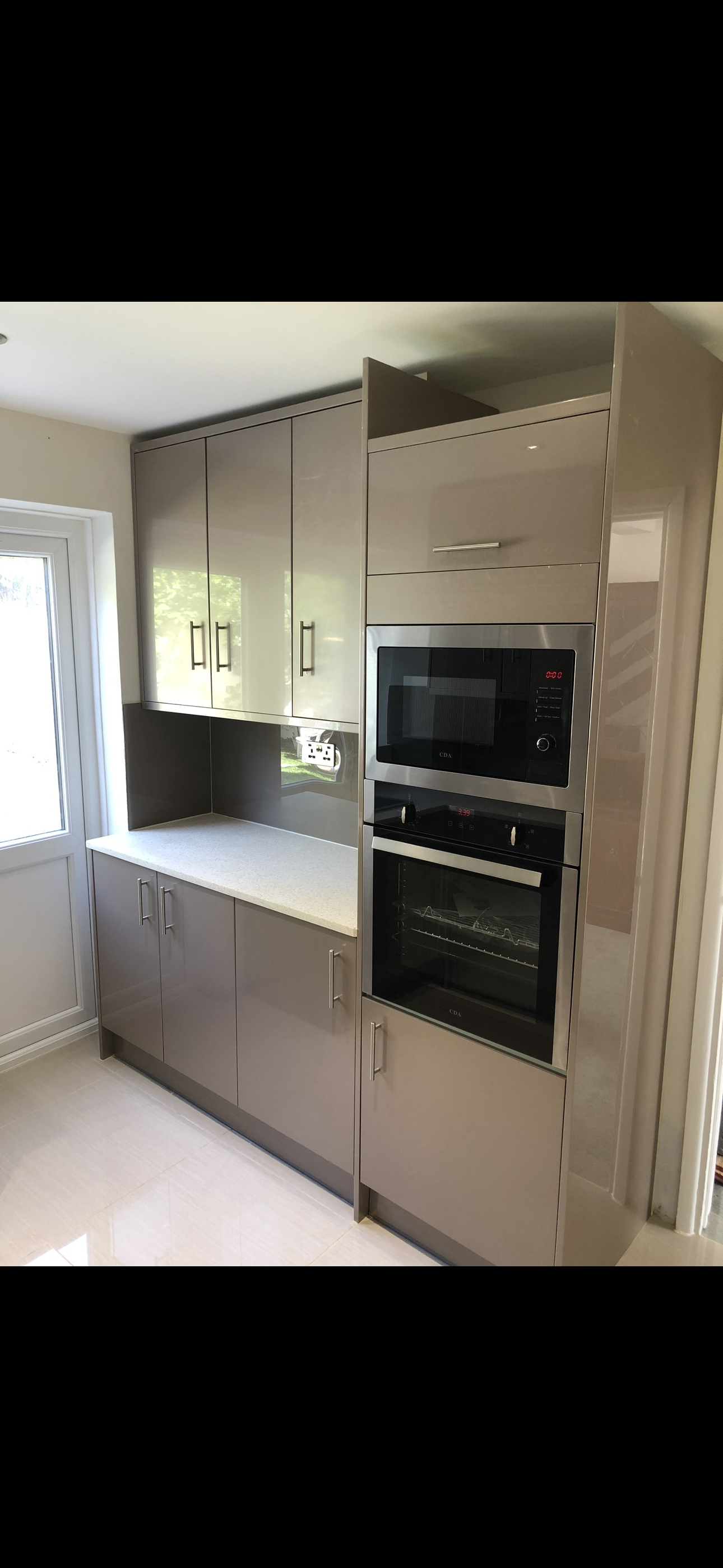 Grey gloss kitchen with full-height tower unit housing integrated microwave and oven
