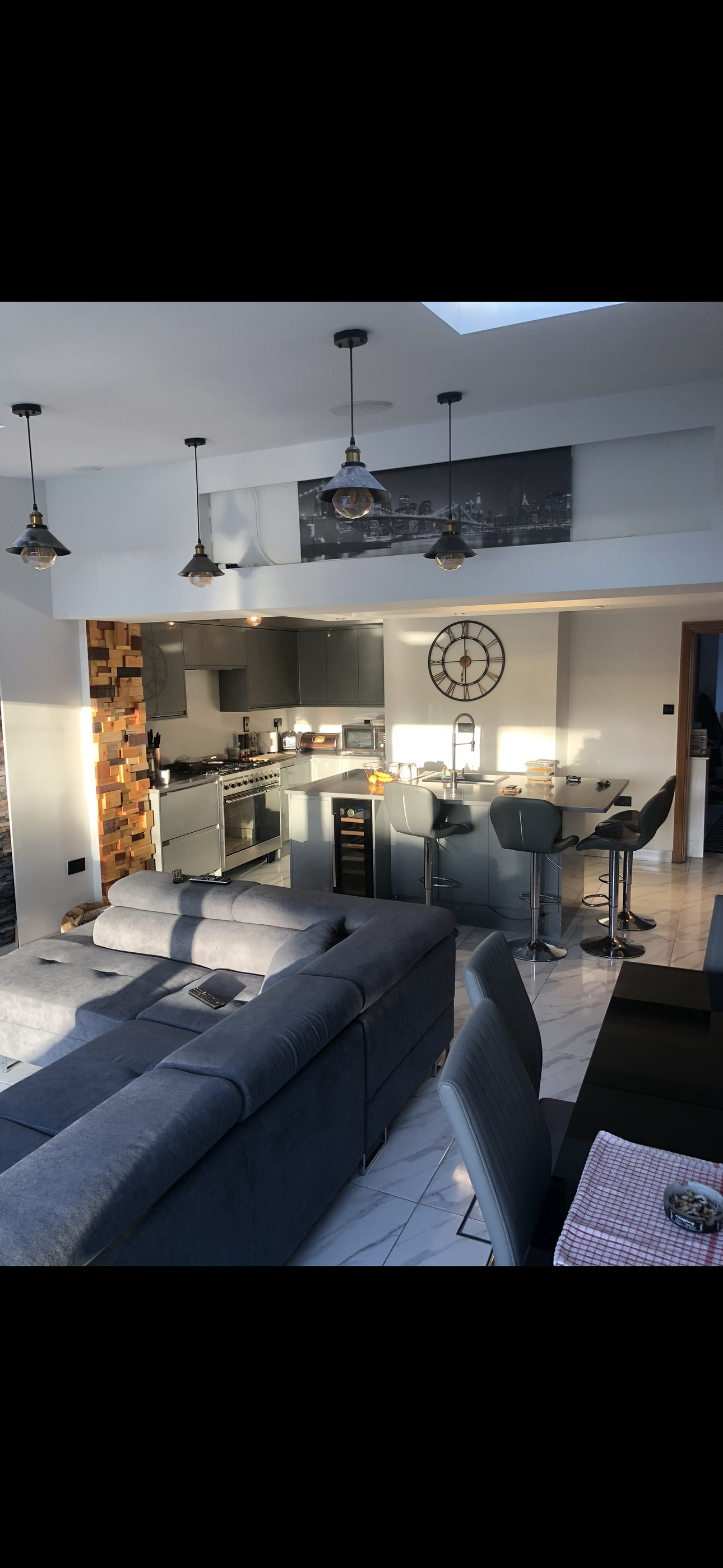 Open-plan dark grey kitchen with range cooker, wine fridge, island and vaulted ceiling with skylights
