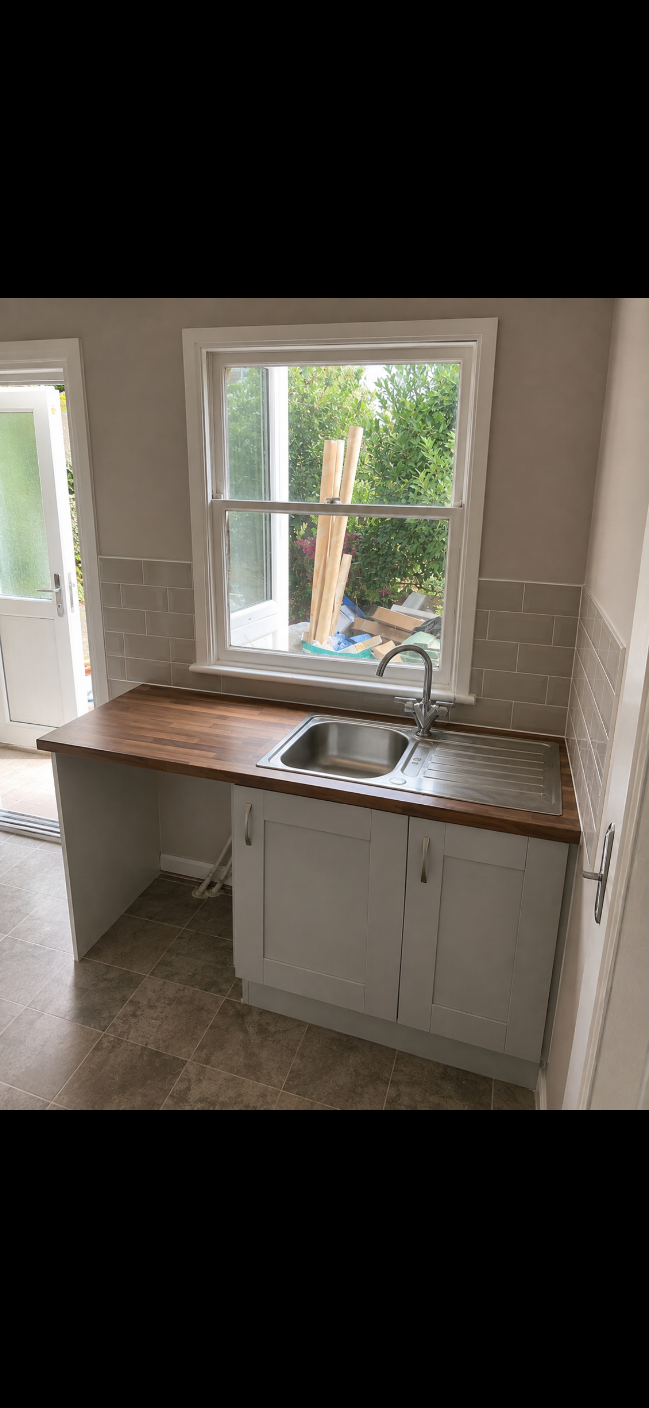 White shaker kitchen with walnut worktop, stainless steel sink and garden-view window