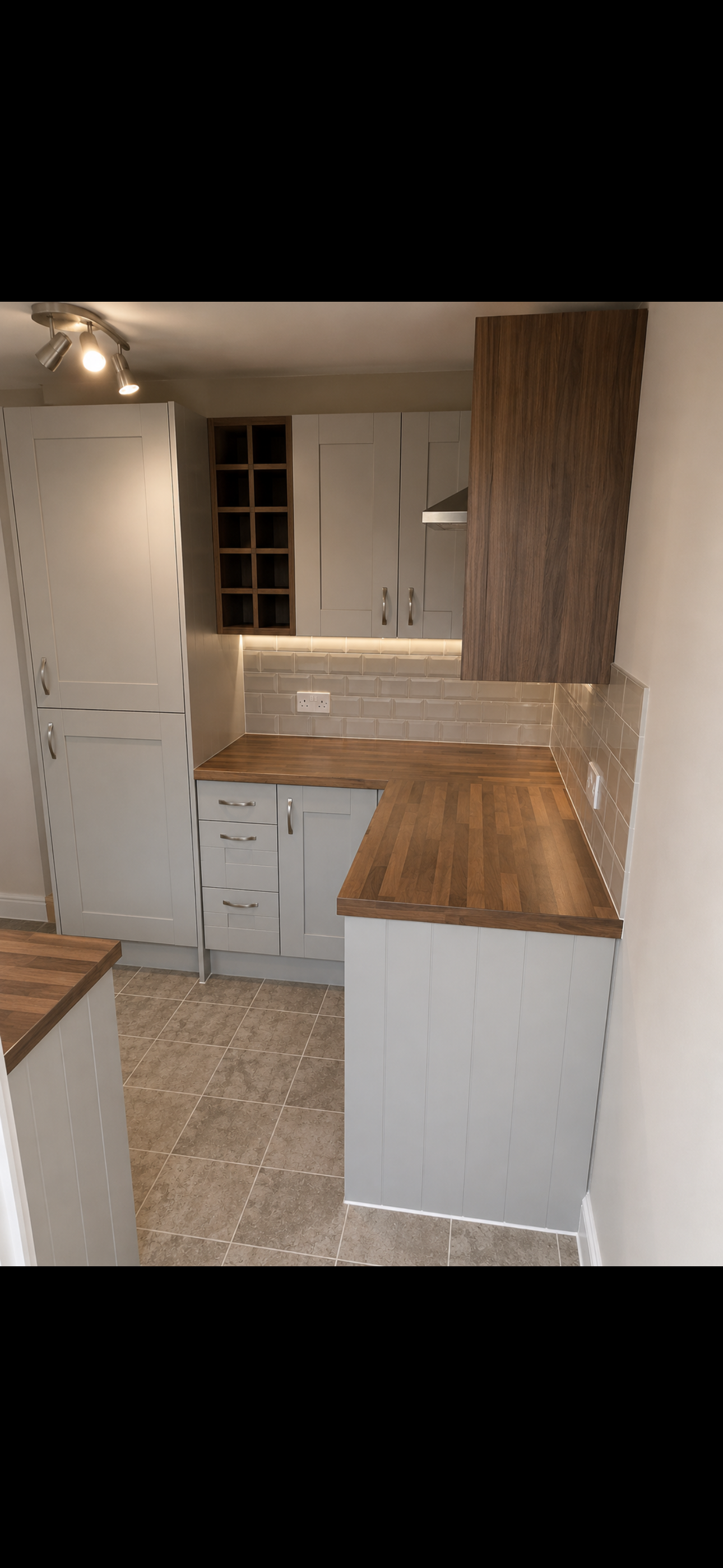 White shaker kitchen with walnut worktop, under-cabinet lighting, subway tile splashback and wine rack