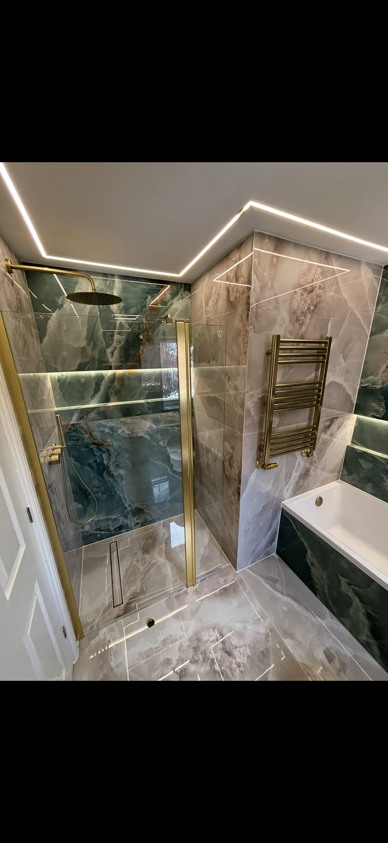 Green marble walk-in shower with gold rain head and heated towel rail